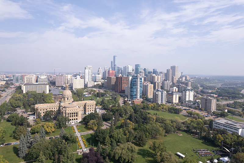 An aerial view of Downtown Edmonton, with a dusty blue sky and trees just starting to turn gold.