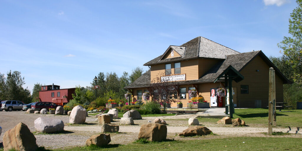 The rustic visitors centre at Stony Plain, small boulders and an old red train car in the yard.