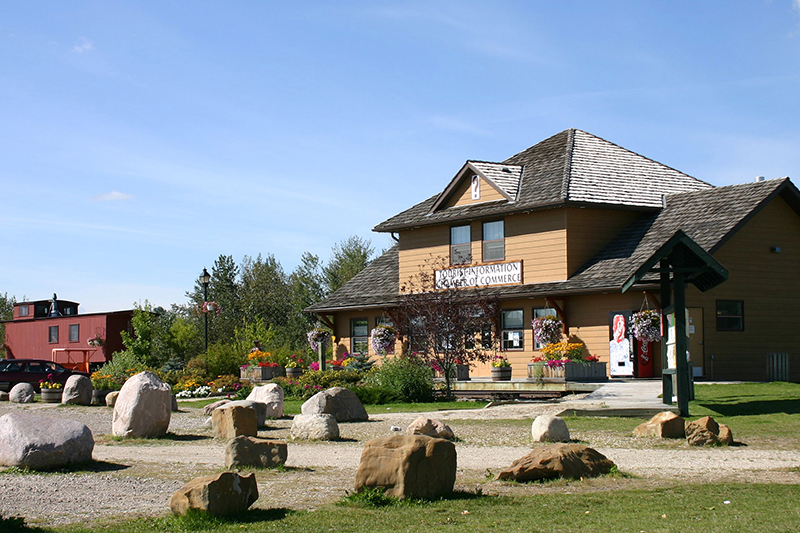 The rustic visitors centre at Stony Plain, small boulders and an old red train car in the yard.