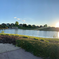 The sun low on the horizon over the Jagare Ridge Golf Club, a lake and homes in the background.