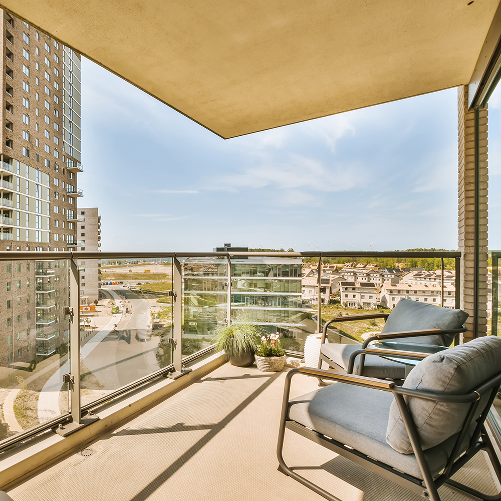 A balcony with chairs and a city view in the background.