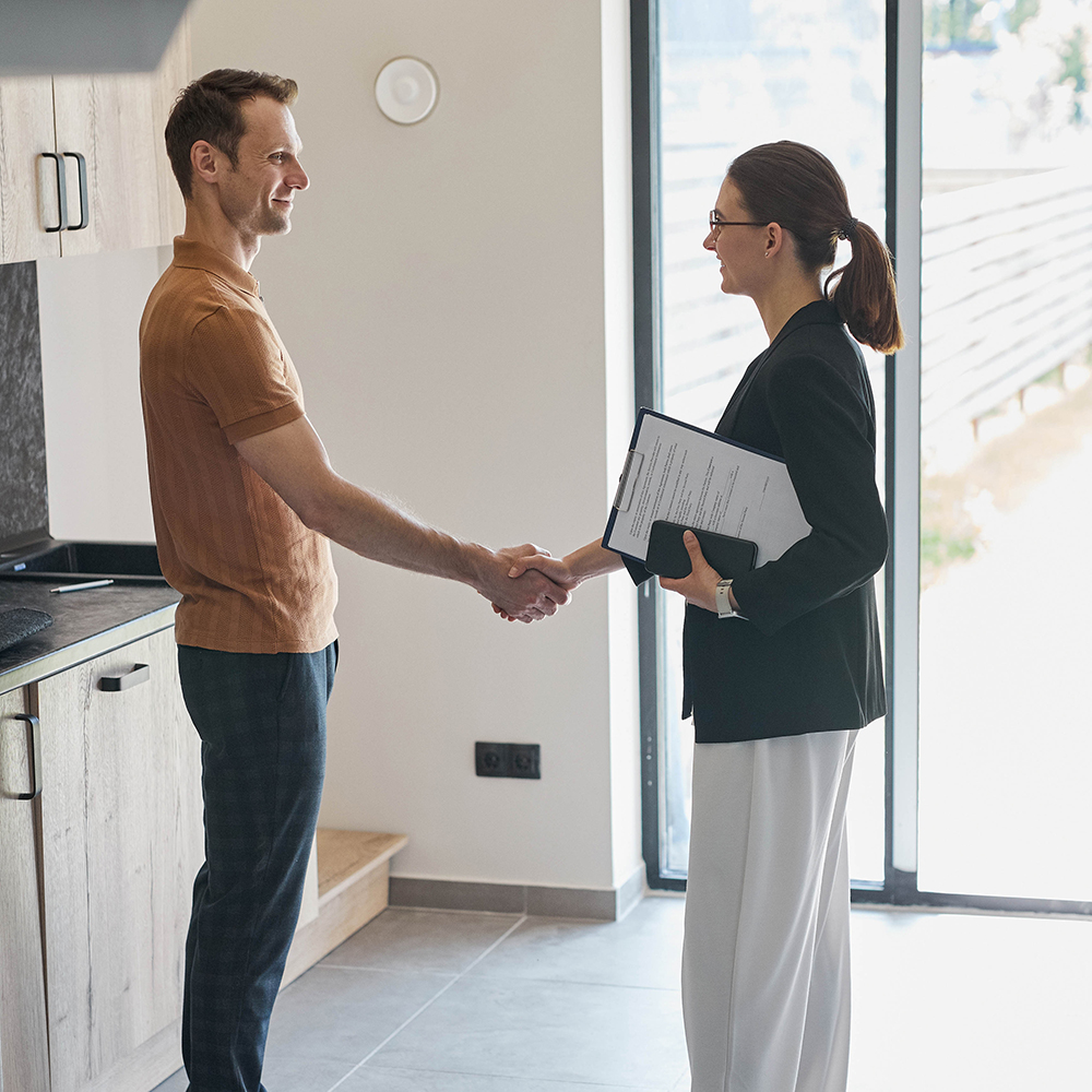 Side view portrait of female real estate agent shaking hands with client.