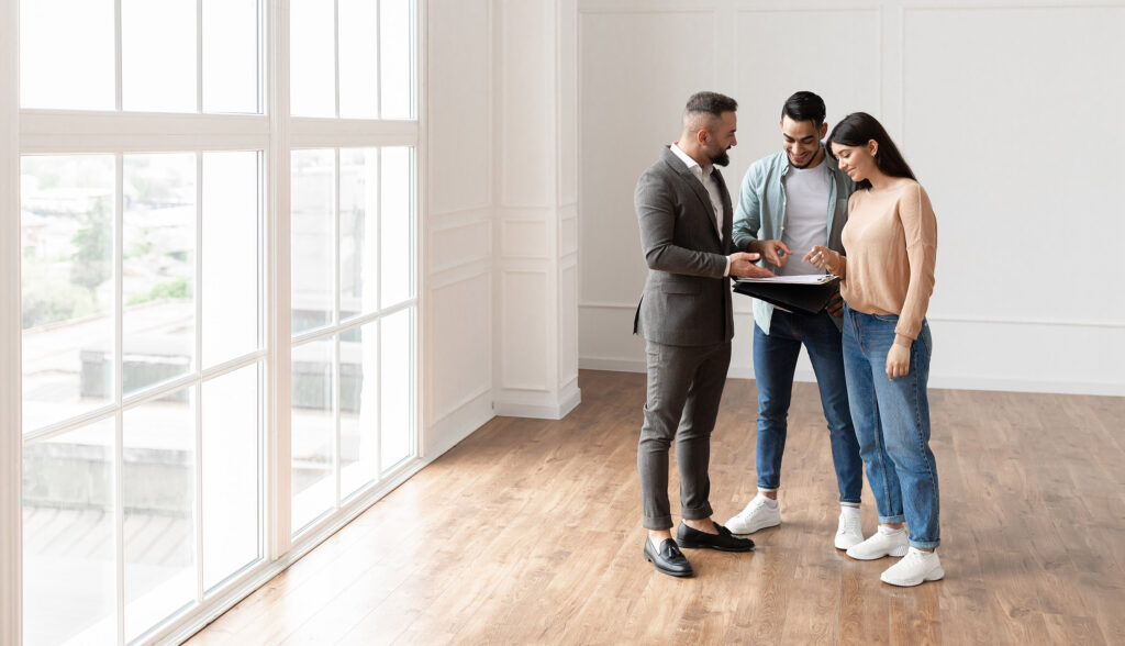 Two people looking at an iPad with a real estate agent.