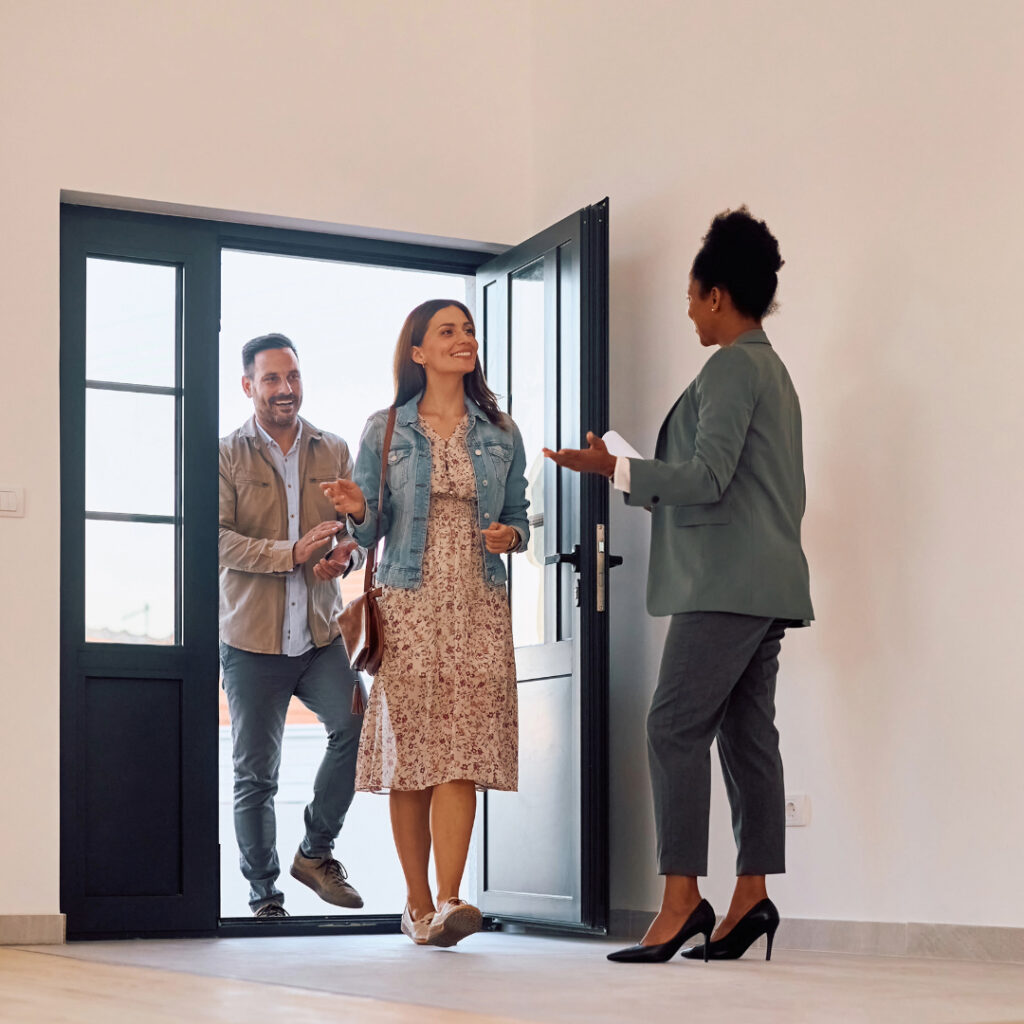 African American real estate agent welcoming couple who is looking for a new house.