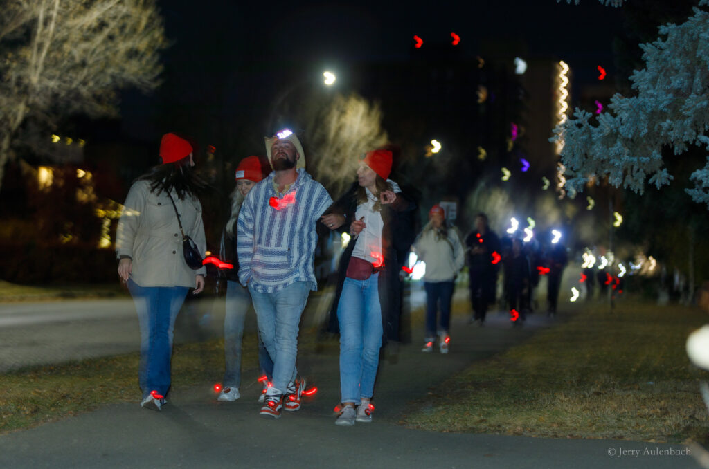 Group of walkers on a quiet evening sidewalk holding lanterns.