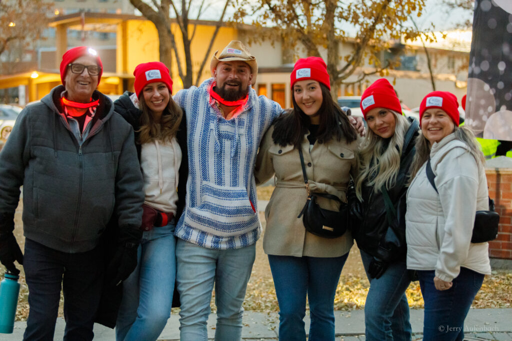 Six smiling friends posing together before the Night Light Walk Edmonton 2025.
