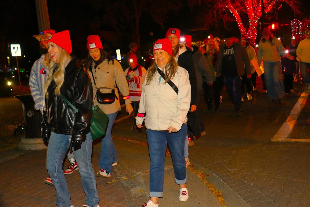 Large group of walkers moving through Edmonton streets at night with lanterns.
