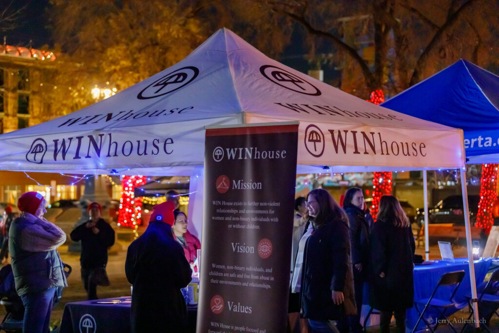 WIN House tent lit up with volunteers sharing information.